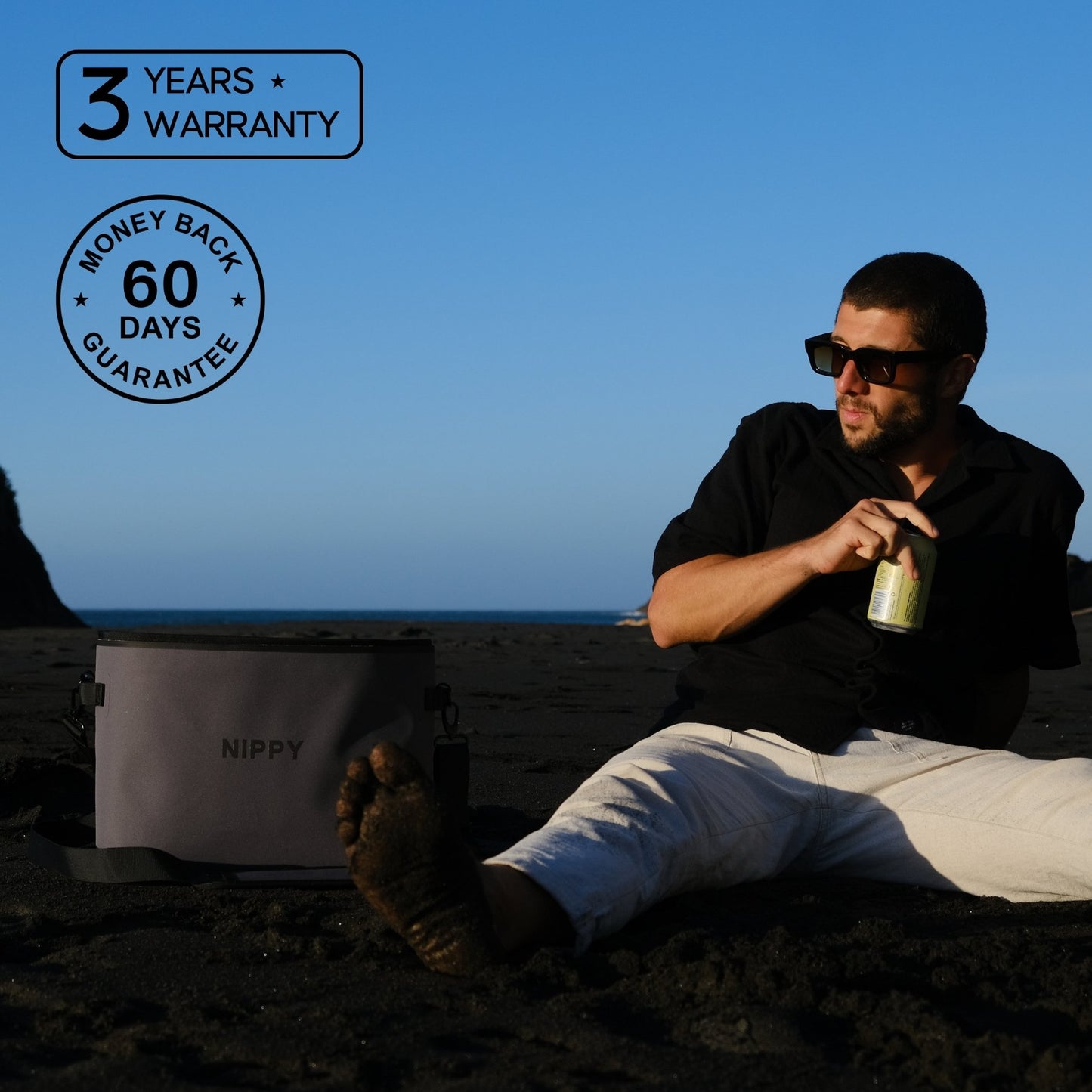 Man sitting on a beach with a Nippy cooler, with text about the 3 year warranty and 60 day money-back guarantee.